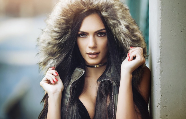 Брюнетка в капюшоне с красными ногтями на руках 