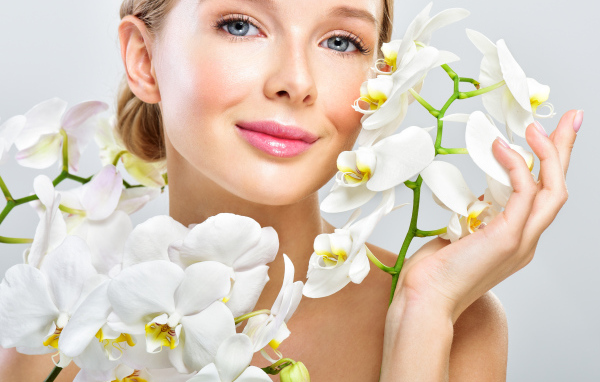 Нежная голубоглазая девушка с цветами орхидеи в руках