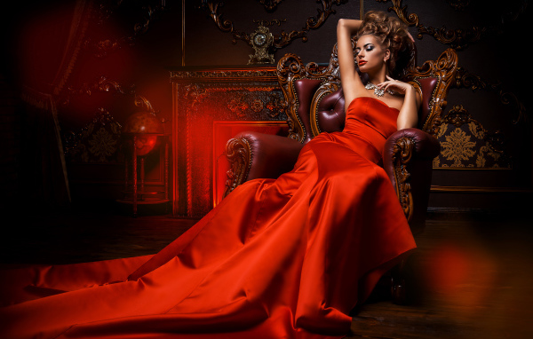 Девушка в красивом красном платье в кресле 