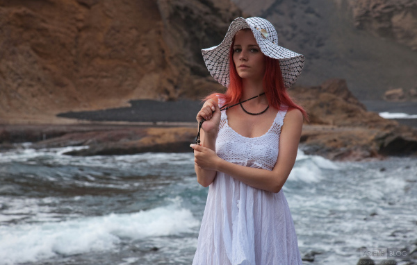 Рыжеволосая девушка в шляпе и белом платье у реки