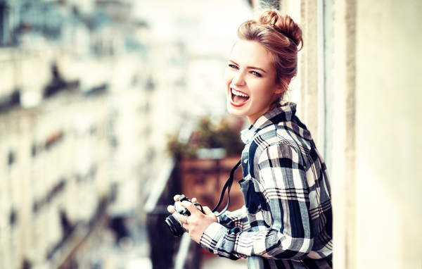 Улыбающаяся девушка в клетчатой рубашке с фотоаппаратом 