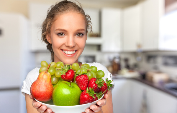 Улыбающаяся девушка со свежими фруктами 
