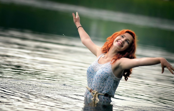 Улыбающаяся рыжеволосая девушка в воде 