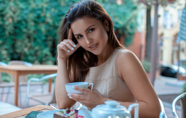 Молодая улыбающаяся девушка с чашкой кофе в кафе