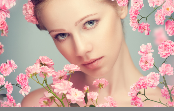 Молодая нежная девушка с розовыми розами на сером фоне