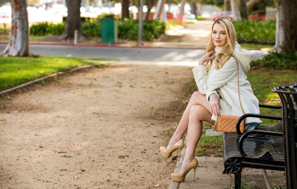 Красивая девушка фотомодель Кенна Джеймс сидит на лавке в парке