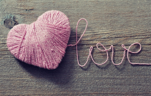 Надпись Love из розовых ниток на деревянном столе