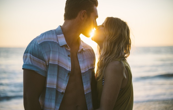 Романтический поцелуй влюбленной пары на закате солнца