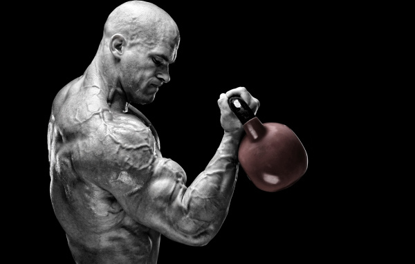 Сильный накаченный мужчина бодибилдер с гантелей в руках