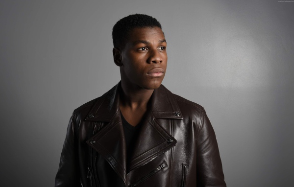 Актер  Джон Бойега в кожаной куртке на сером фоне