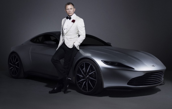 Знаменитый актер Дэниел Крэйг рядом с серебристым автомобилем Aston Martin