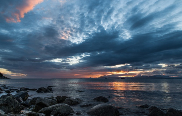 Валуны в воде на берегу на фоне пасмурного неба 