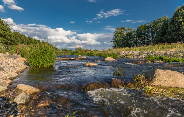 Быстрая речная вода стекает по камням под красивым голубым небом