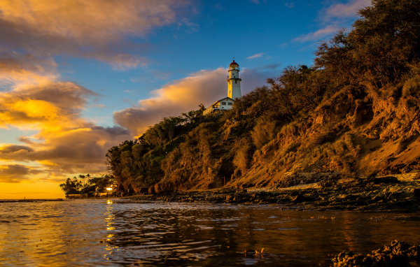 Маяк на склоне скалы на закате 