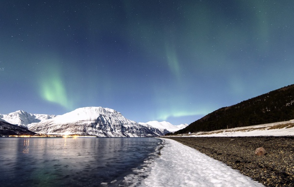 Северное сияние в небе над заснеженными горами 