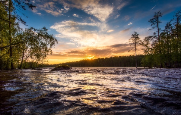 Sunrise of the summer sun over the fast river