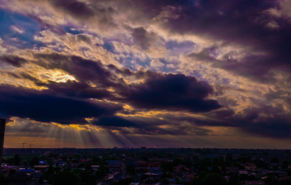 Лучи солнца пробиваются сквозь облака над городом