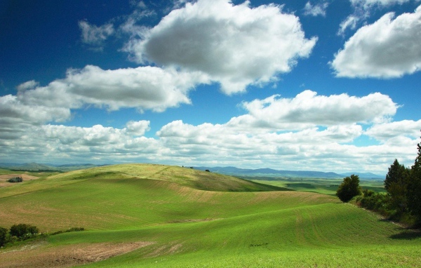 Белые облака в голубом небе над зеленой равниной