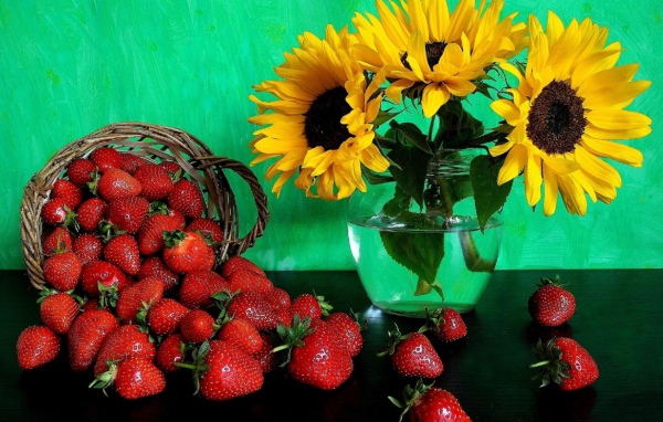 Цветы желтого подсолнуха в вазе со свежей клубникой 