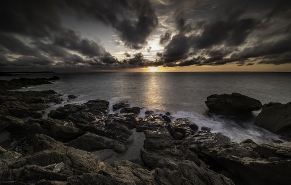 Низкие черные облака на закате в небе над океаном