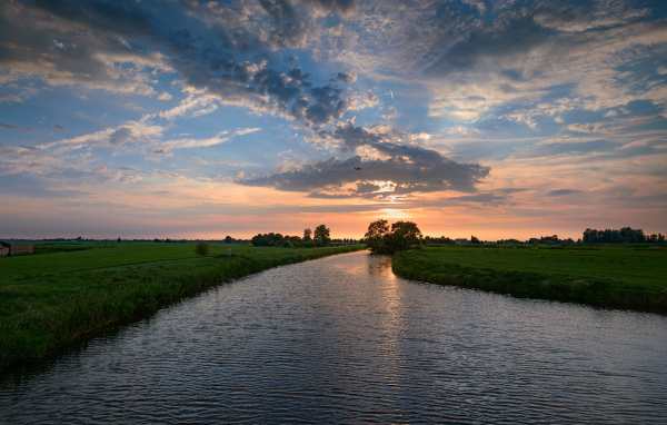 Закат солнца в облаках  над спокойной рекой