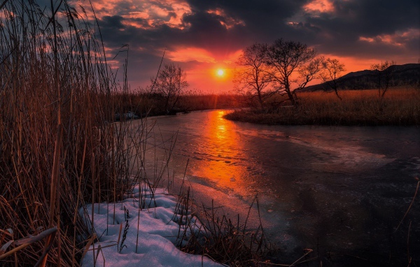Закат солнца над покрытой льдом рекой