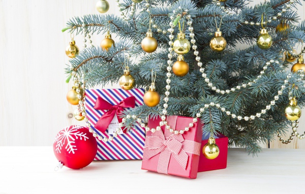 Подарки под зеленой наряженной елкой с золотыми шарами