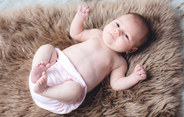 Грудной ребенок лежит на меховом покрывале