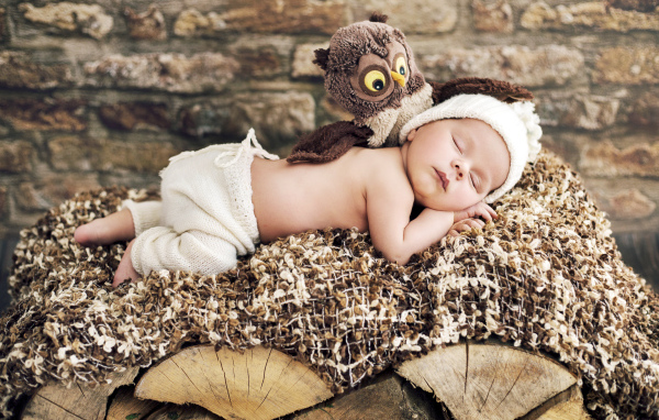 Грудной ребенок спит рядом с игрушкой совой