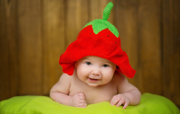 Младенец в забавной шапке клубнике на голове