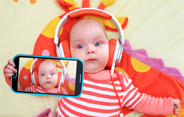 Младенец в оранжевых наушниках делает селфи