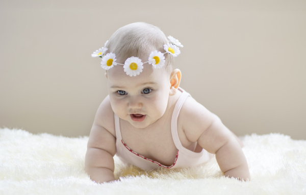 Грудной ребенок с венком из белых ромашек на голове
