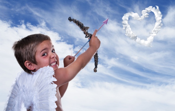 Мальчик в костюме купидона пускает стрелу в небо