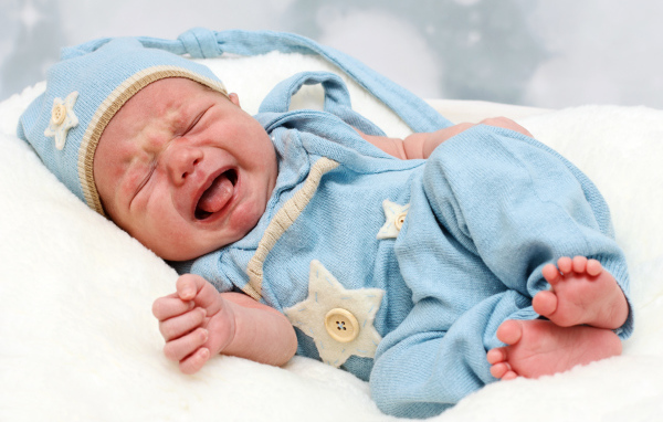 Плачущий младенец в голубом костюме
