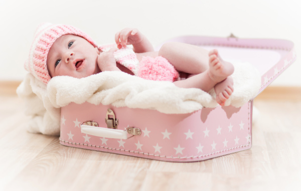 Милый младенец лежит в розовом чемодане