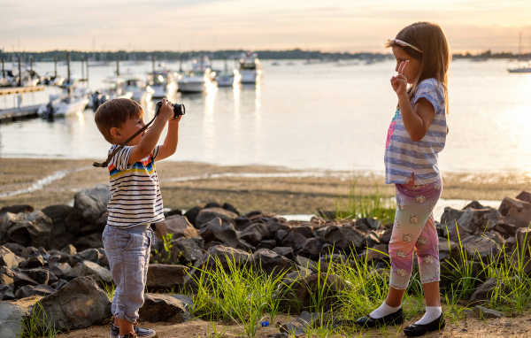 Маленький мальчик фотографирует девочку на берегу