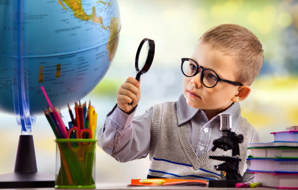 Маленький мальчик в очках исследует глобус