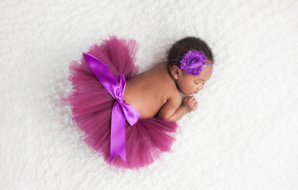 Маленькая девочка в красивой пышной юбке спит на белом покрывале