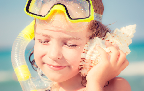 Маленькая девочка приложила ракушку к уху