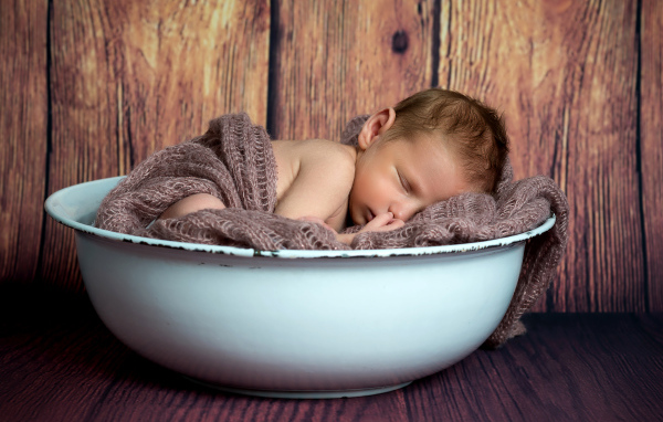 Новорожденный ребенок спит в белой миске