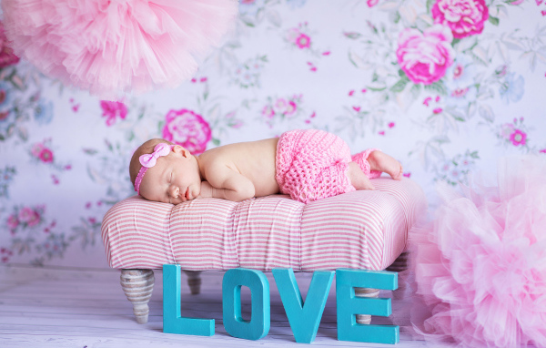 Спящий грудной ребенок в розовом костюме и надписью love
