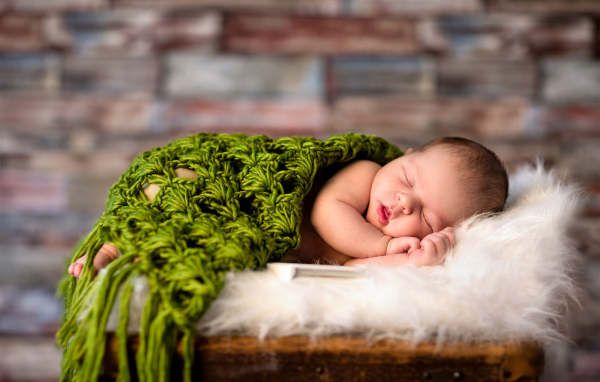 Спящий младенец под зеленым вязаным пледом