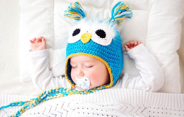 Спящий ребенок в забавной вязаной шапке