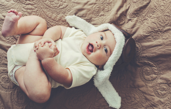 Маленький грудной ребенок лежит в шапке летчика