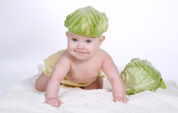 Маленький грудной ребенок с капустным листом на голове