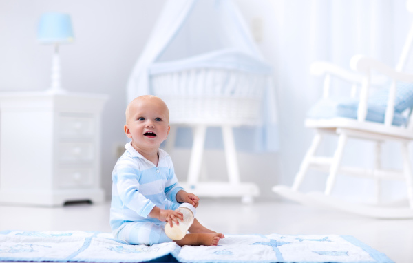 Маленький голубоглазый мальчик сидит на полу в комнате