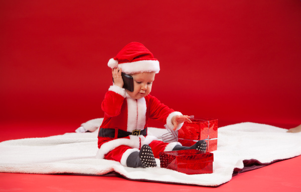 Маленький ребенок в новогодней униформе с подарками