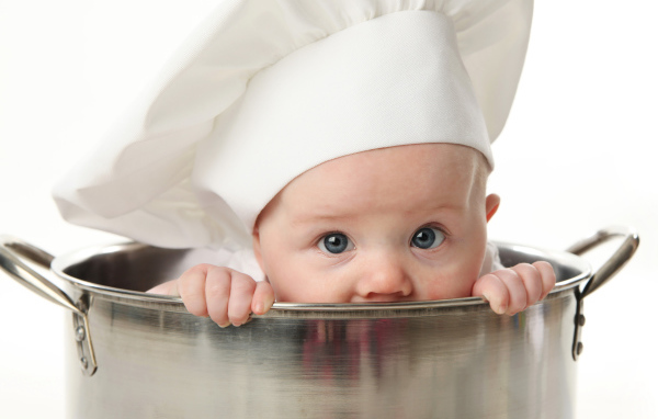 Маленький ребенок сидит в большой железной кастрюле