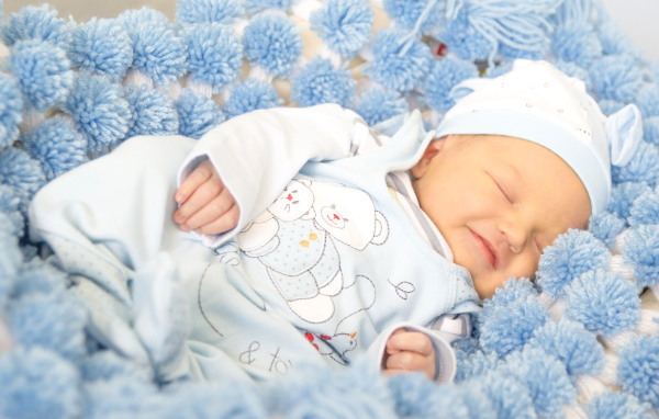 Младенец мальчик улыбается во сне