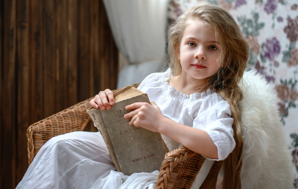 Красивая маленькая девочка в белом платье с книгой 